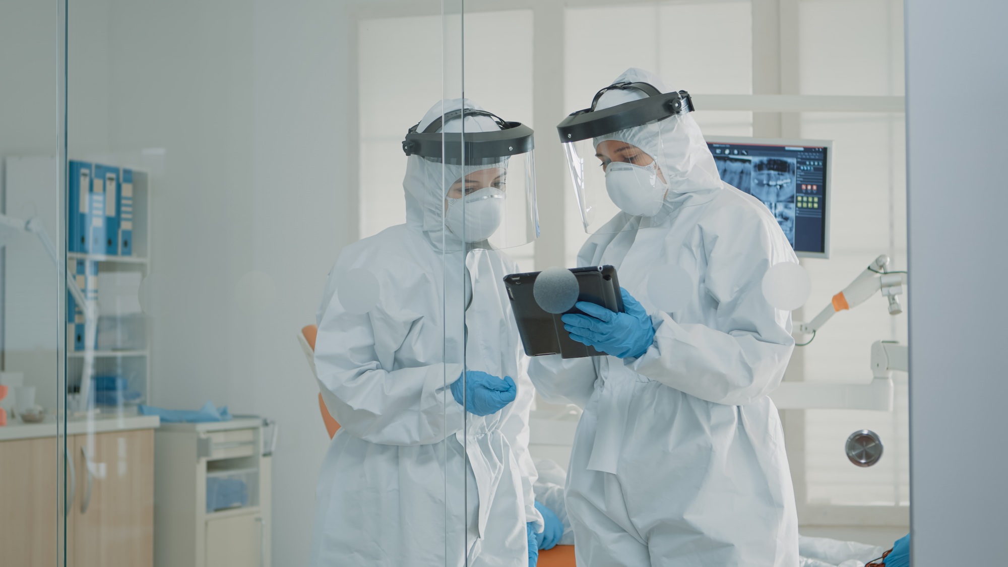 Orthodontists wearing protection suits looking at tablet