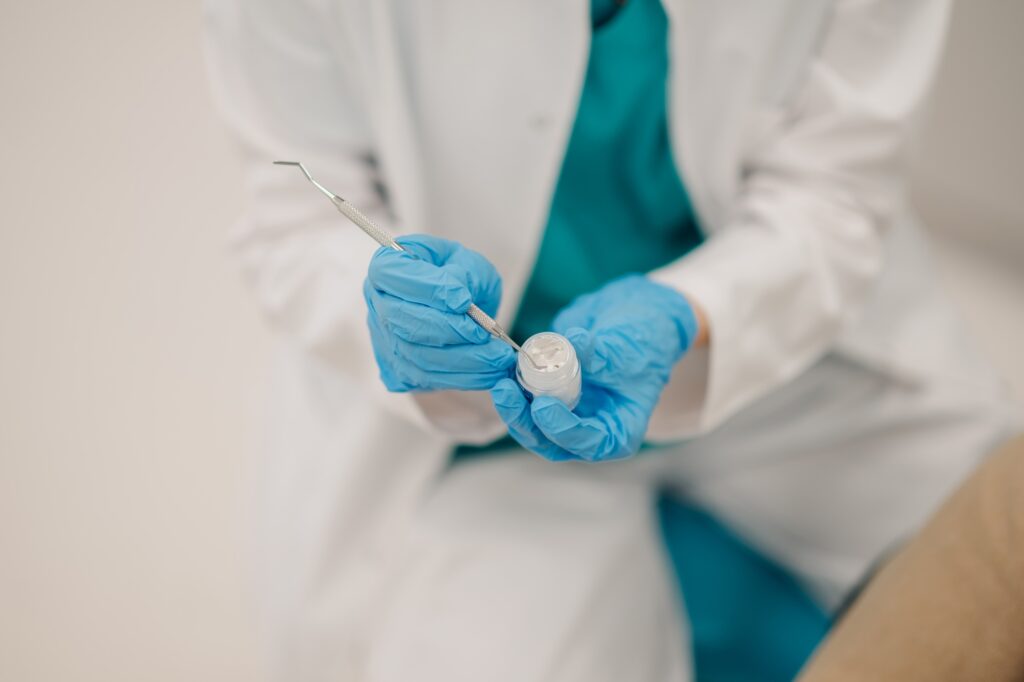 Dentist picking up filling material with dental probe for treatment