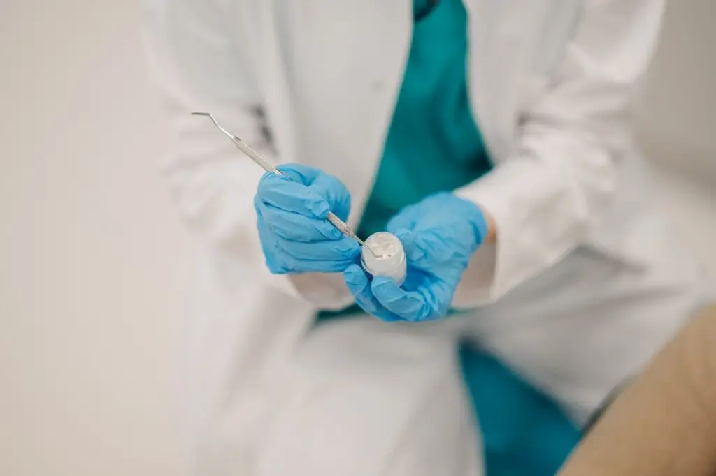 Dentist picking up filling material with dental probe for treatment